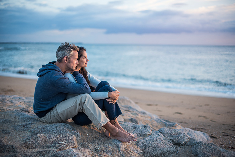 Couple sitting on a rock looking out on the beach