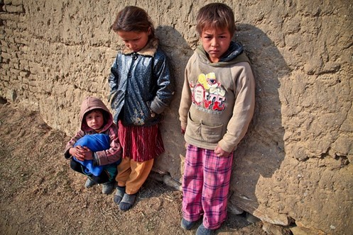 Three unhappy children leaning against a wall