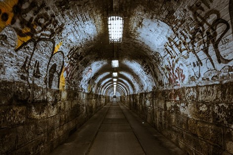 A dark subway tunnel with graffiti on the walls