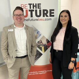 Two people in front of banner